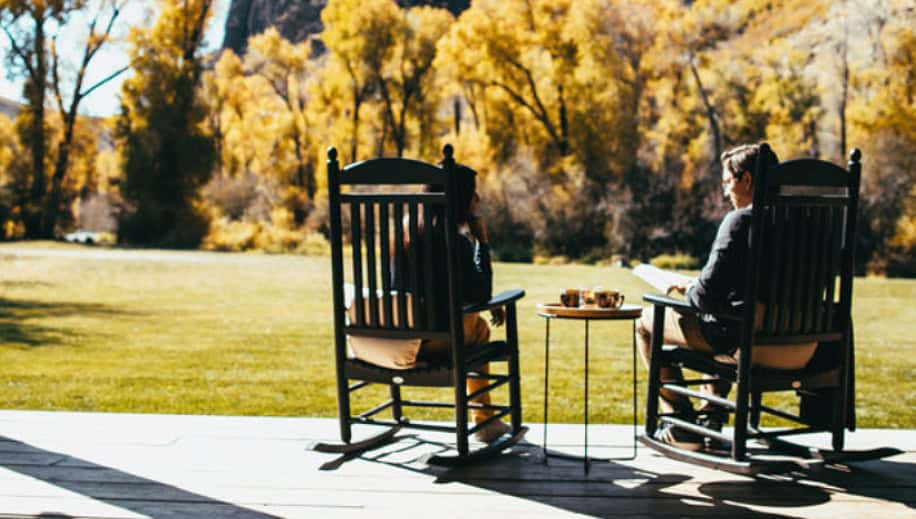 two people sitting in rocking chars outside