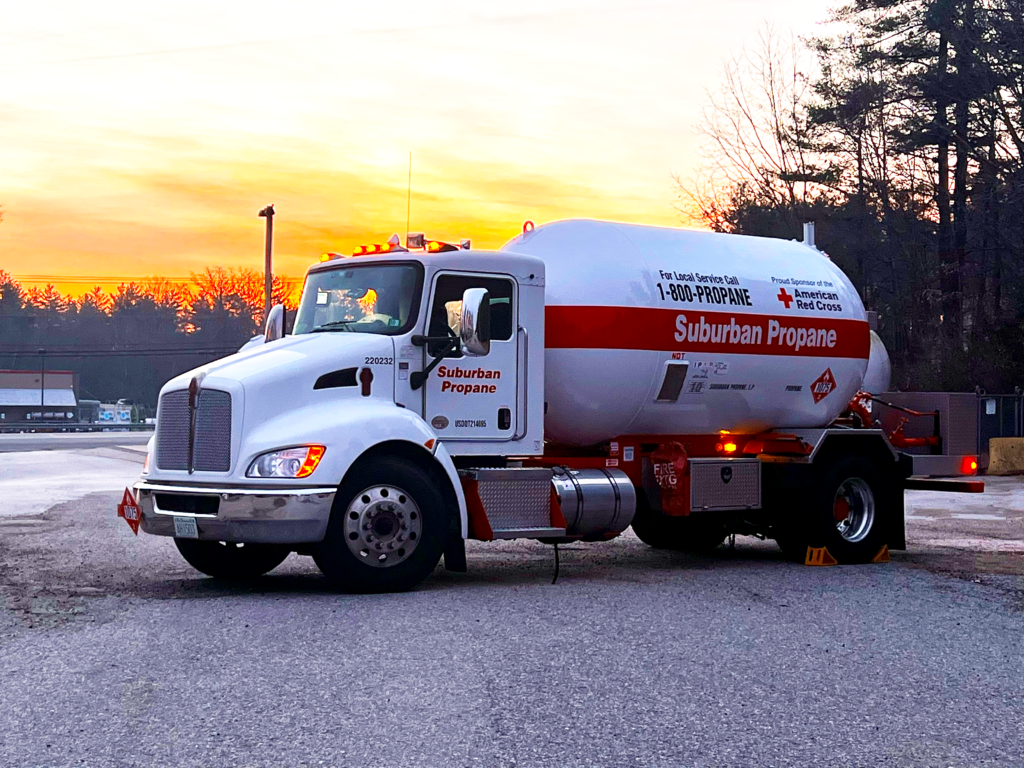 A Suburban Propane trucked parked in the middle of the road at sunset.