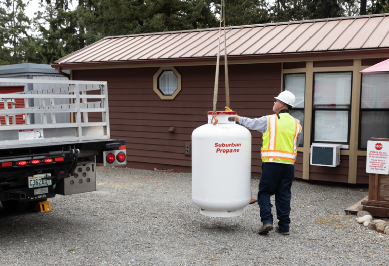 A Suburban Propane worker lowering a propane tank off a delivery truck
