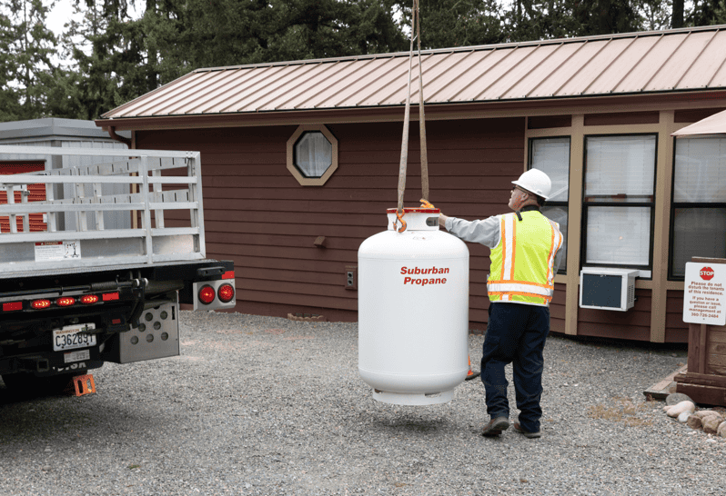 A Suburban Propane worker lowering a propane tank off a delivery truck