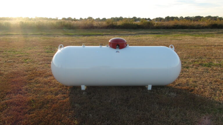 A propane tank in a farm field at dawn
