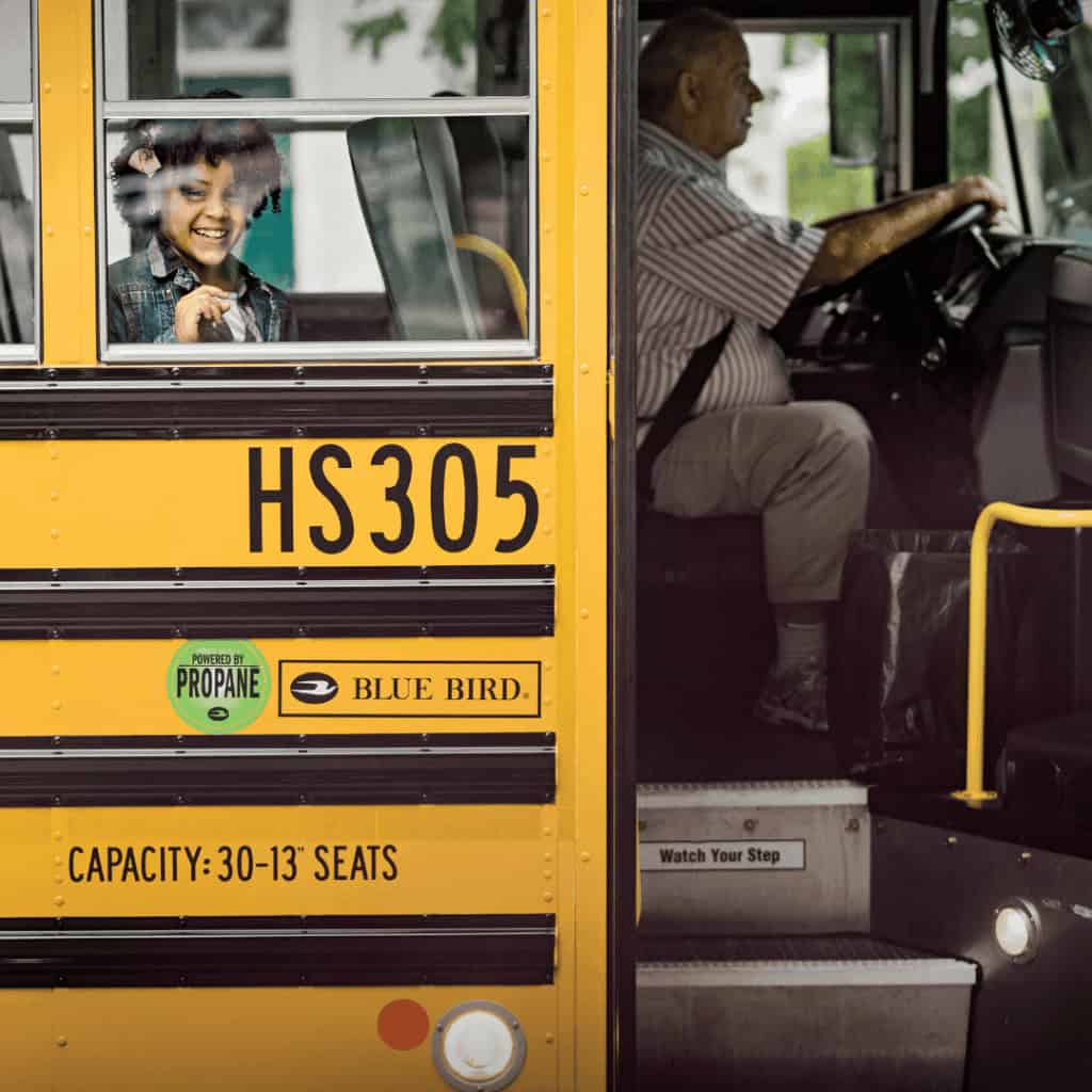 little girl looking outside the window of a school bus